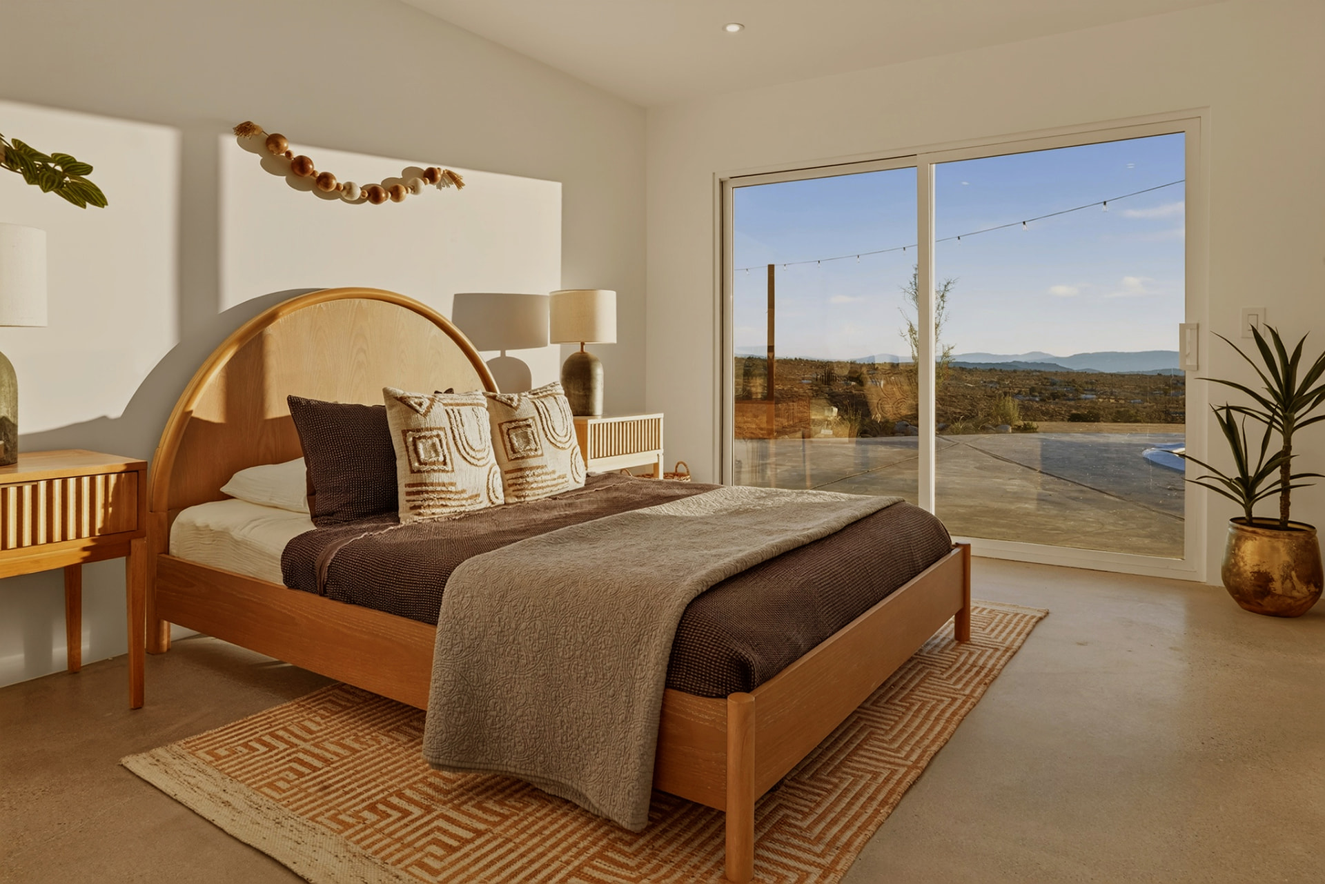 Bedroom with arched wood headboard and sliding doors to the pool deck